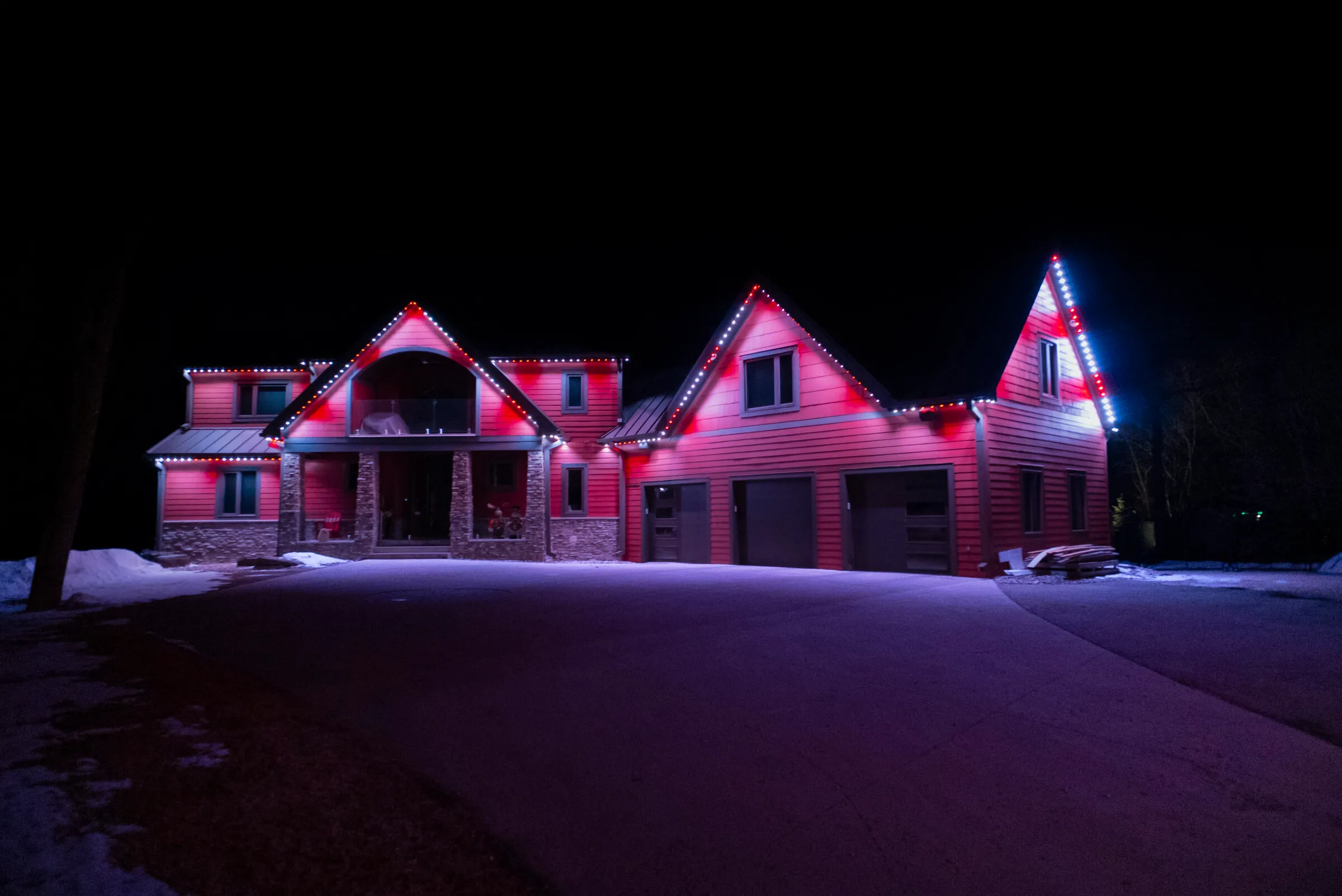 Ranch house in snow with red and white roofline lights