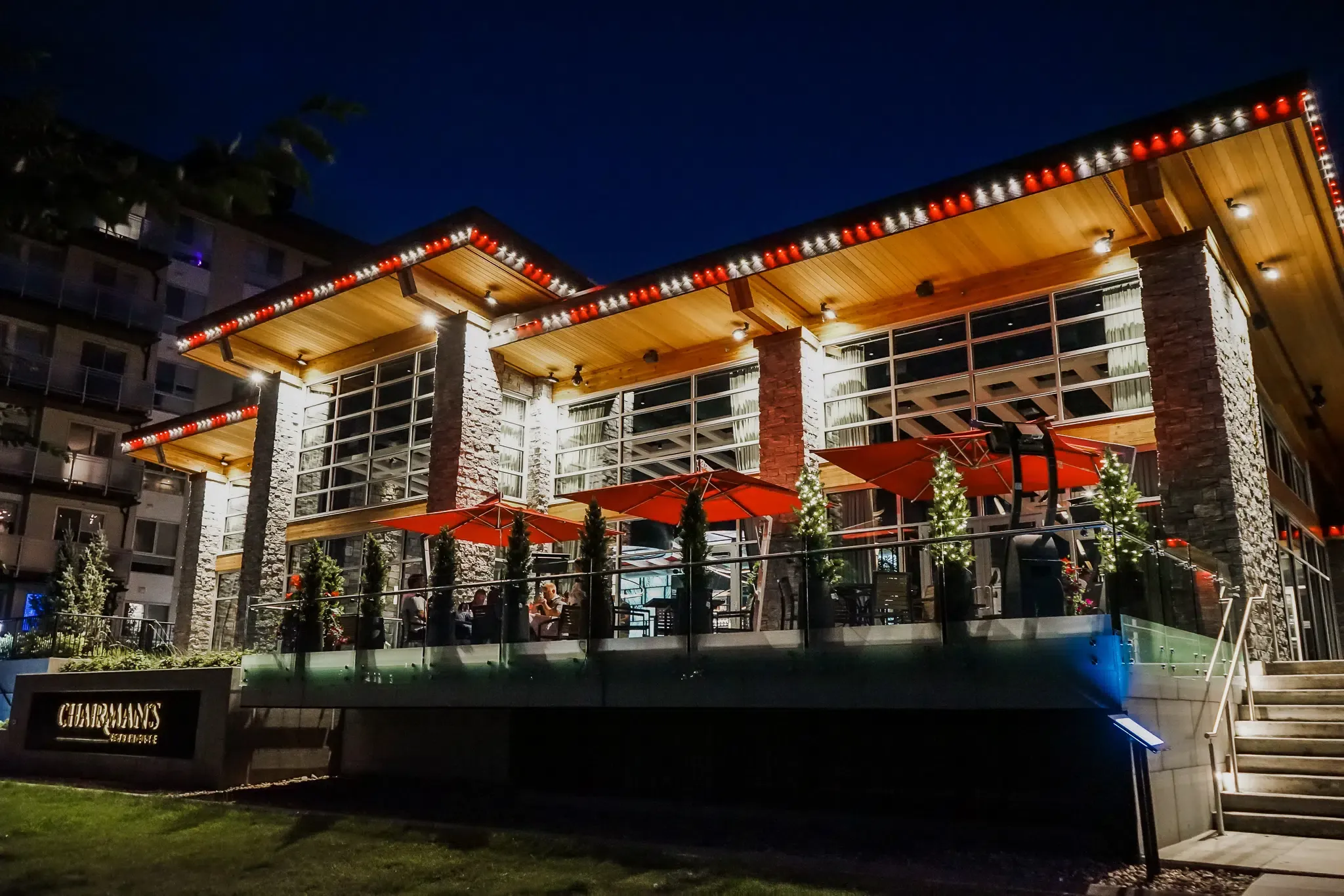Restaurant patio at night with red and white lights along the roofline