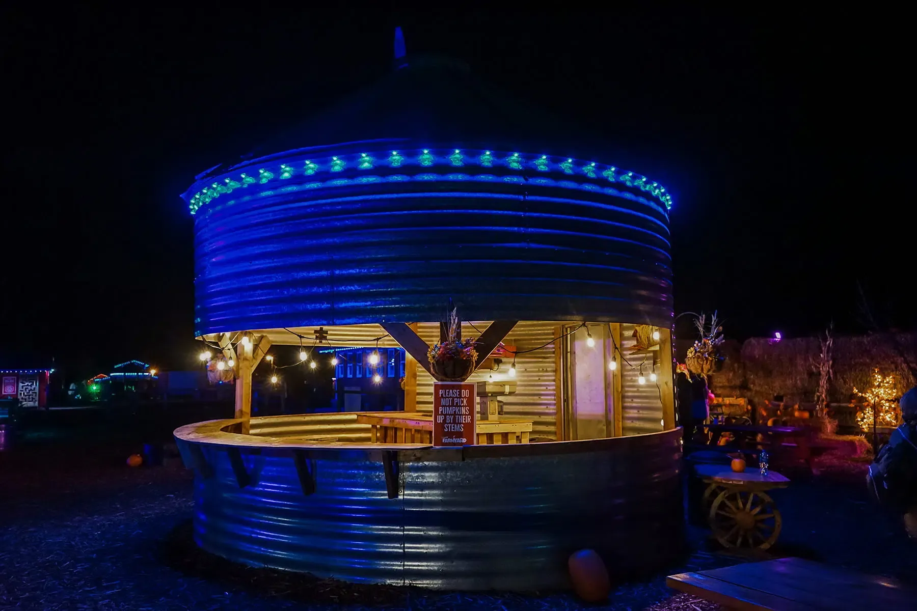Round metal kiosk lit blue around the top at night