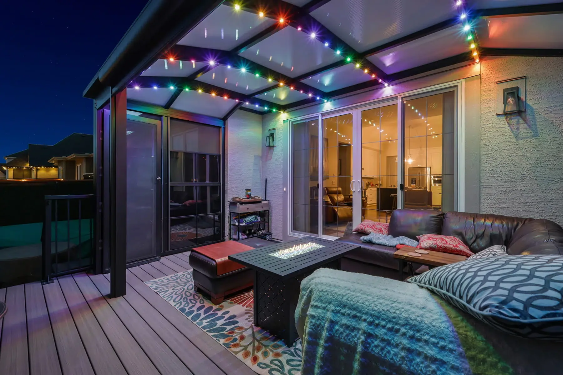 Covered patio at dusk with colourful string lights along the pergola beams above an outdoor sofa