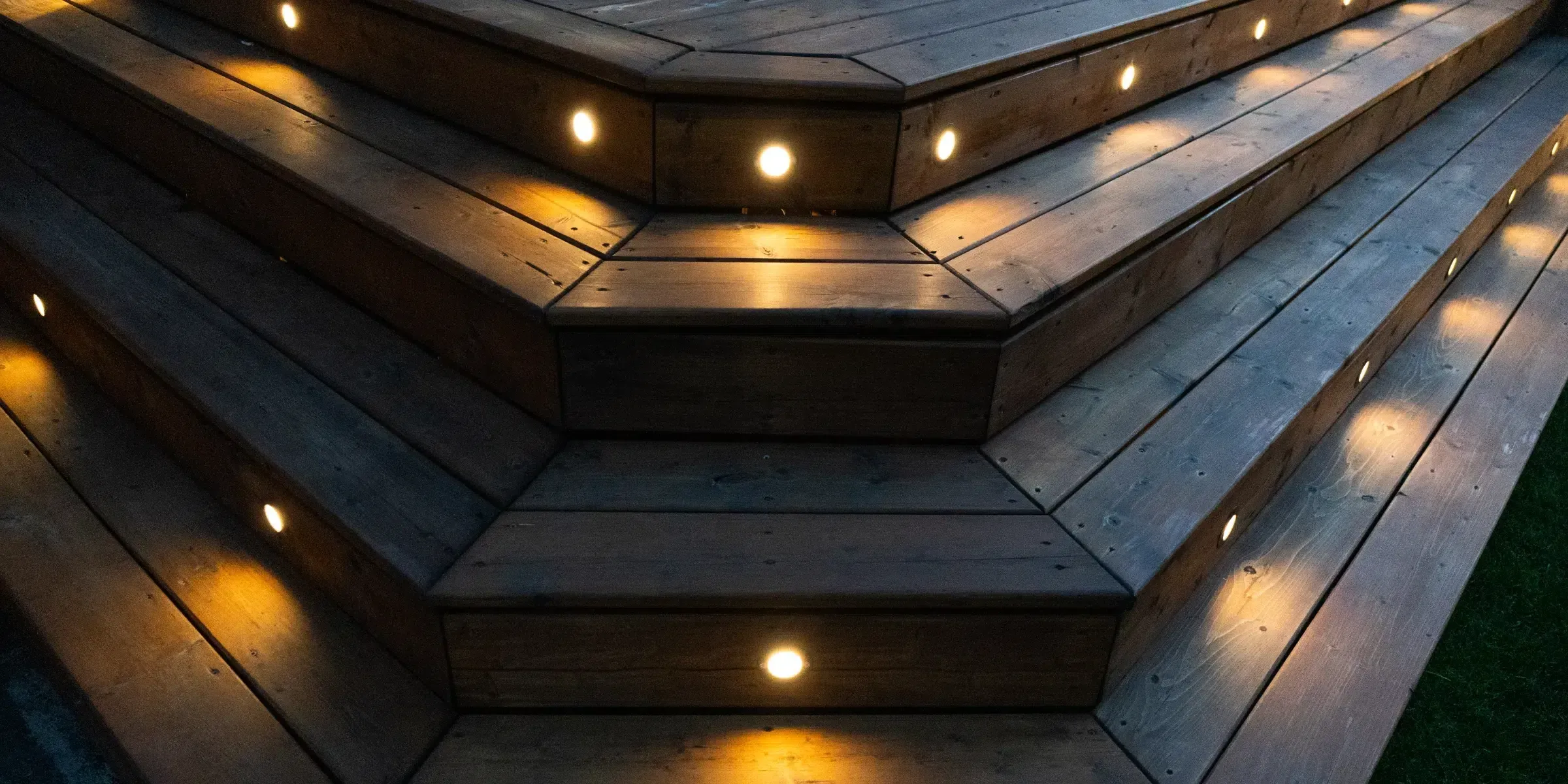 Wide wooden deck steps with warm lights in each riser