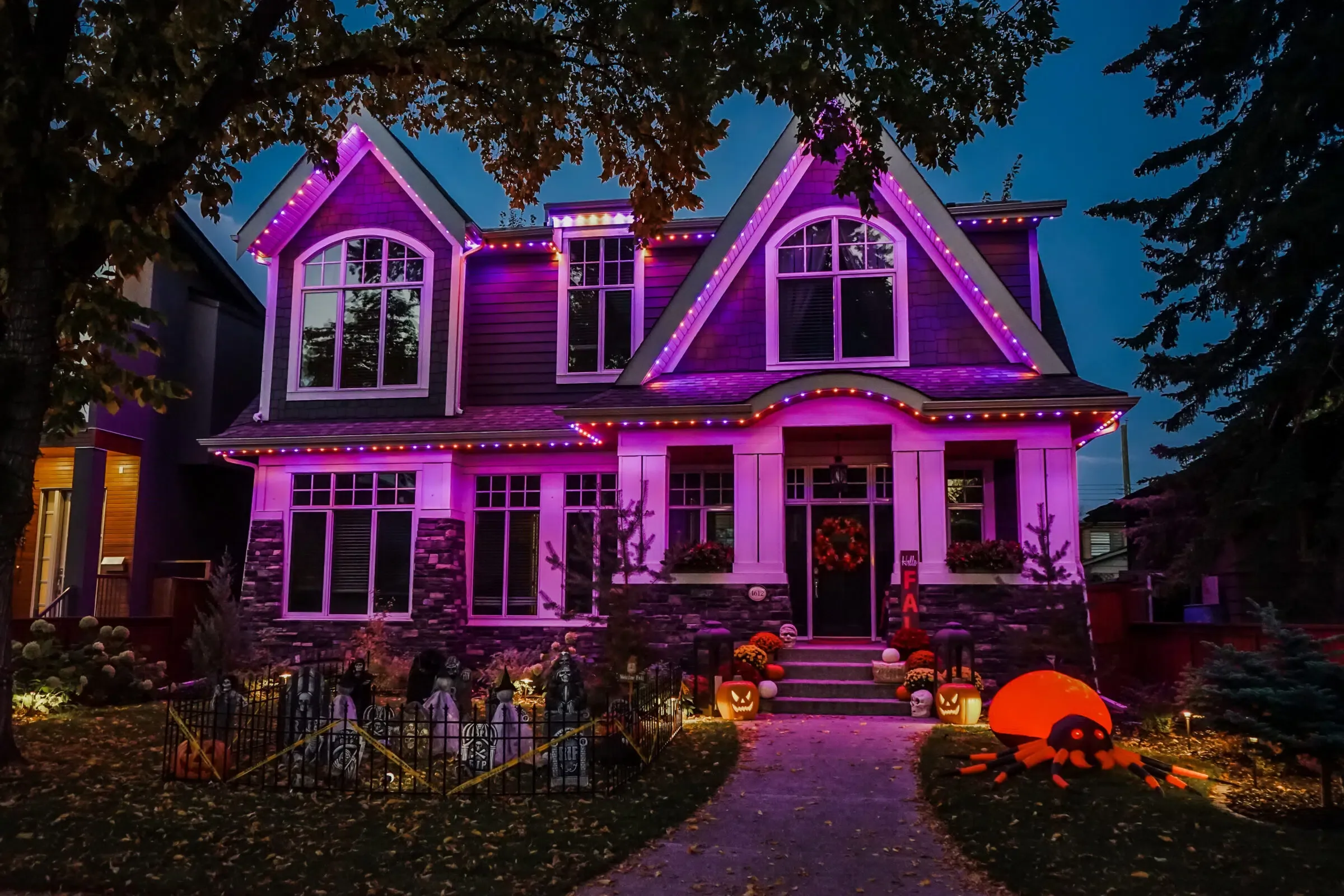 Craftsman house washed in purple with pumpkins on the lawn