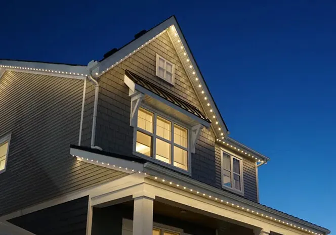 Two-storey house at dusk with white lights along the gables