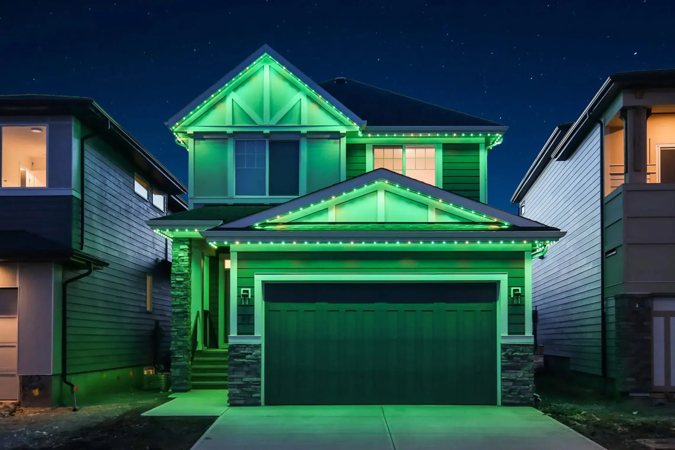 Two-storey house lit bright green along the rooflines