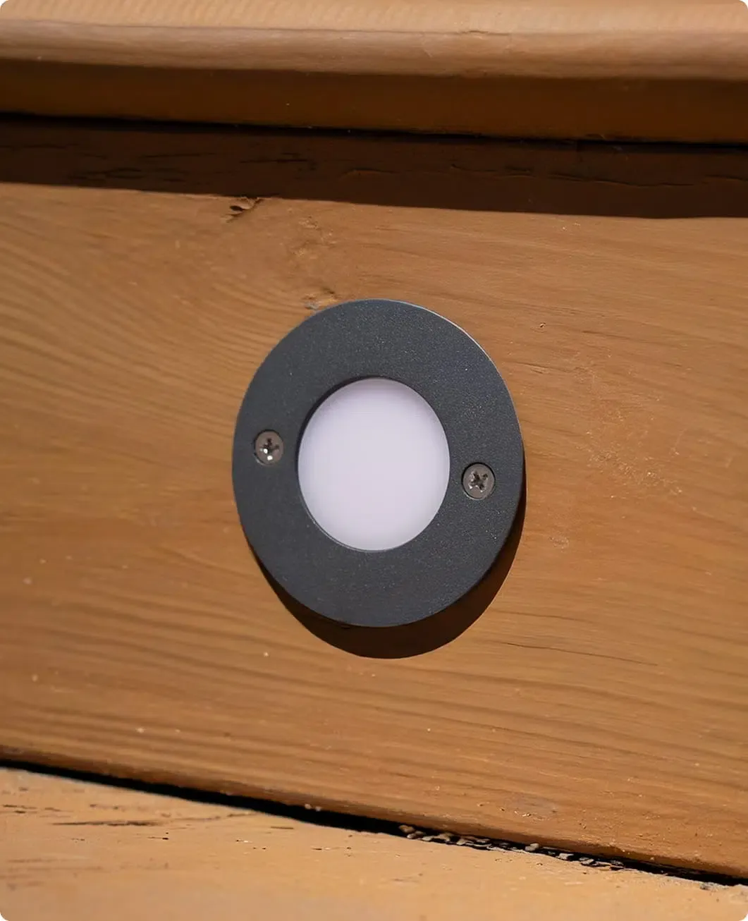 Close-up of a round deck light in a dark metal ring