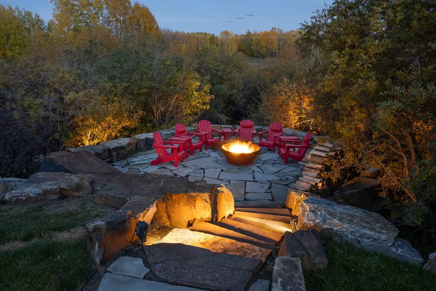 Stone fire pit with red chairs lit warm white