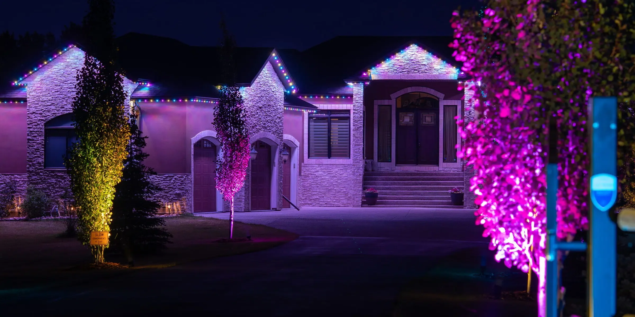 House with magenta and green light on the trees