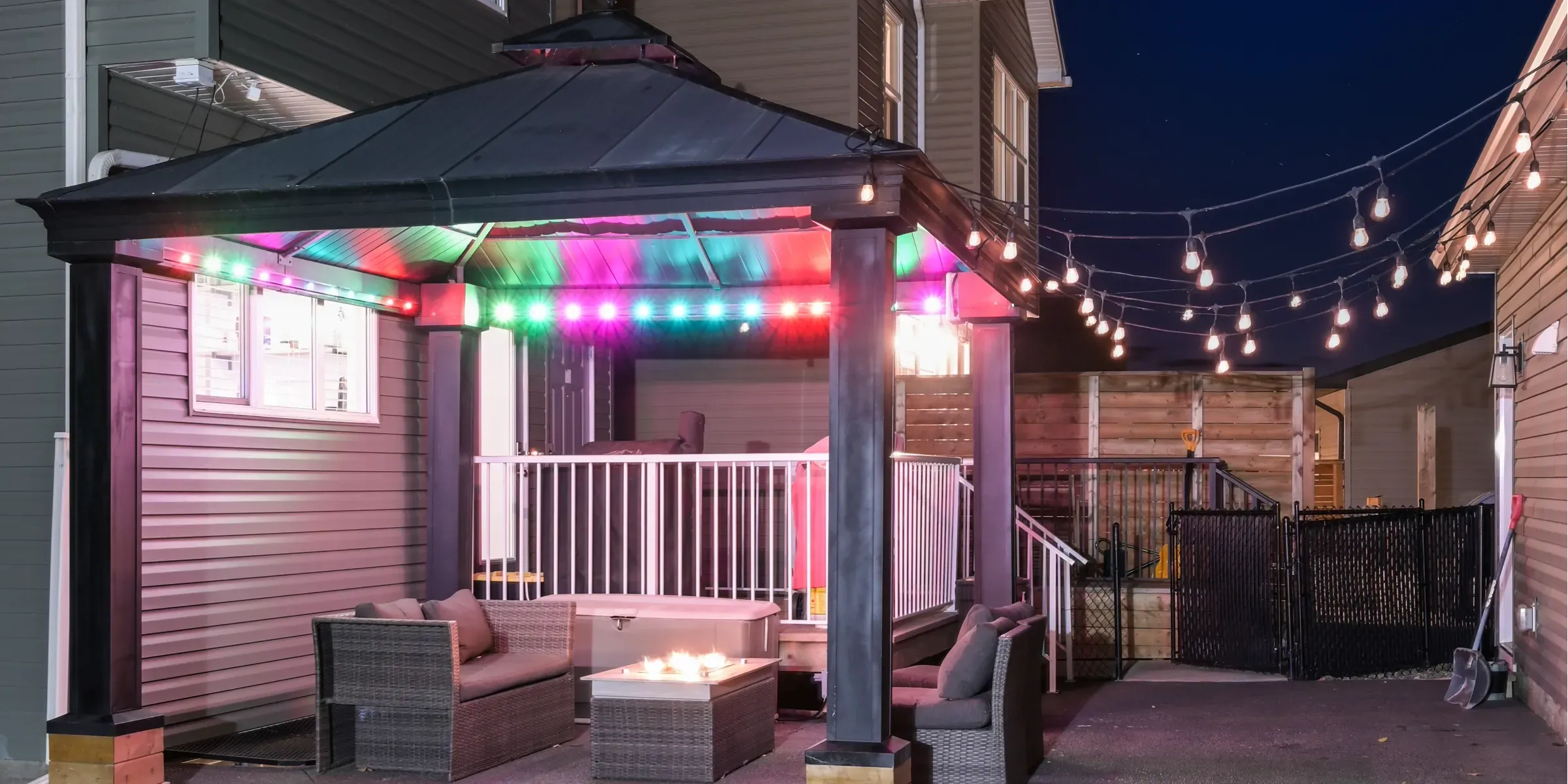 Backyard gazebo with colourful lights and string lights to the house
