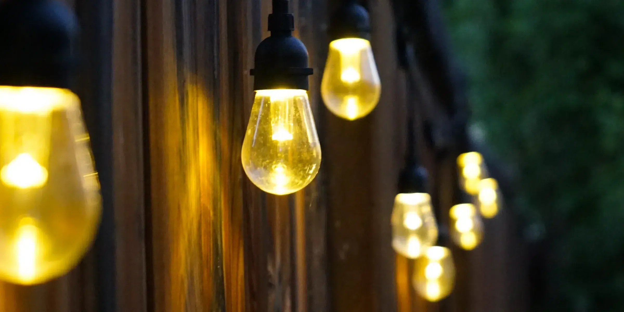 Warm white string light bulbs along a wooden fence