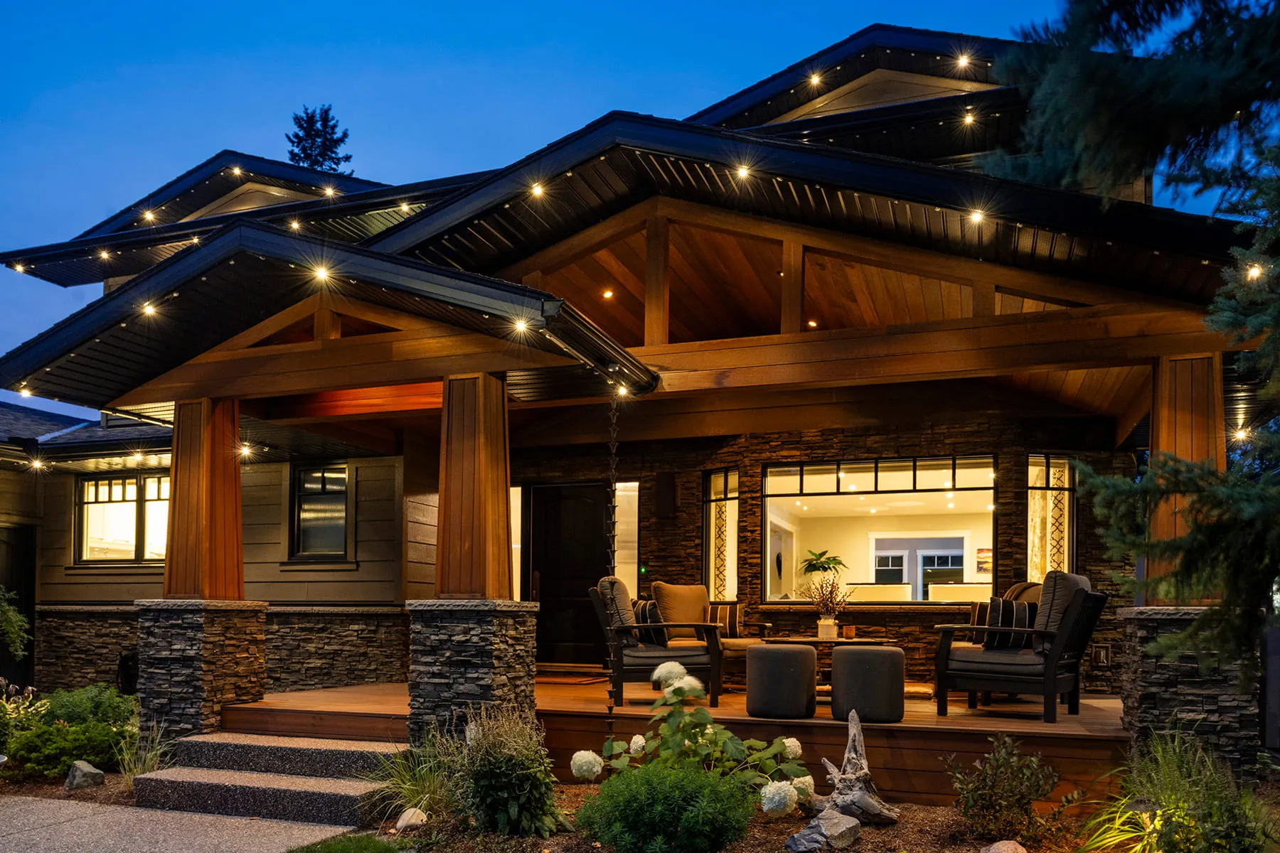 Craftsman-style house at dusk with warm white lights along every roofline