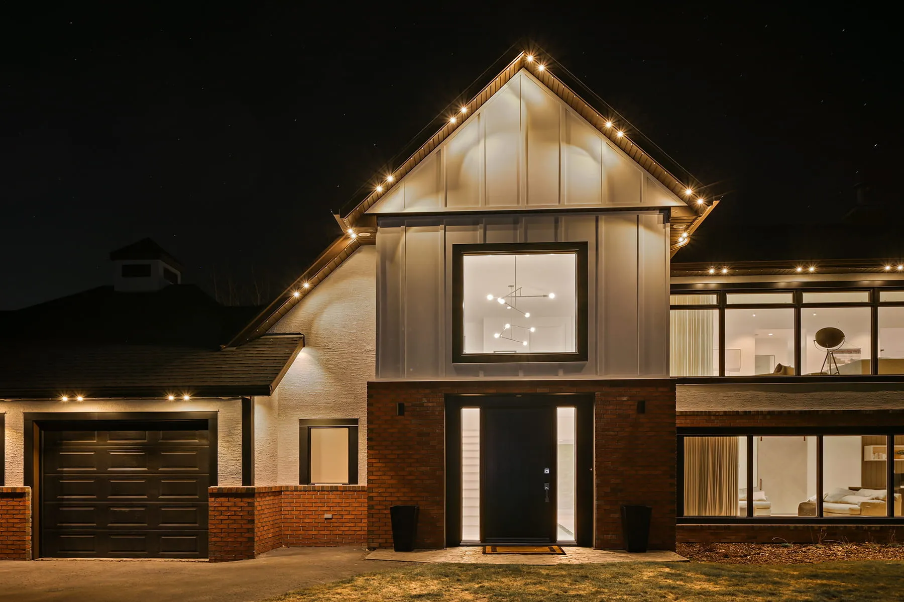 Modern farmhouse at night with warm white roofline lights