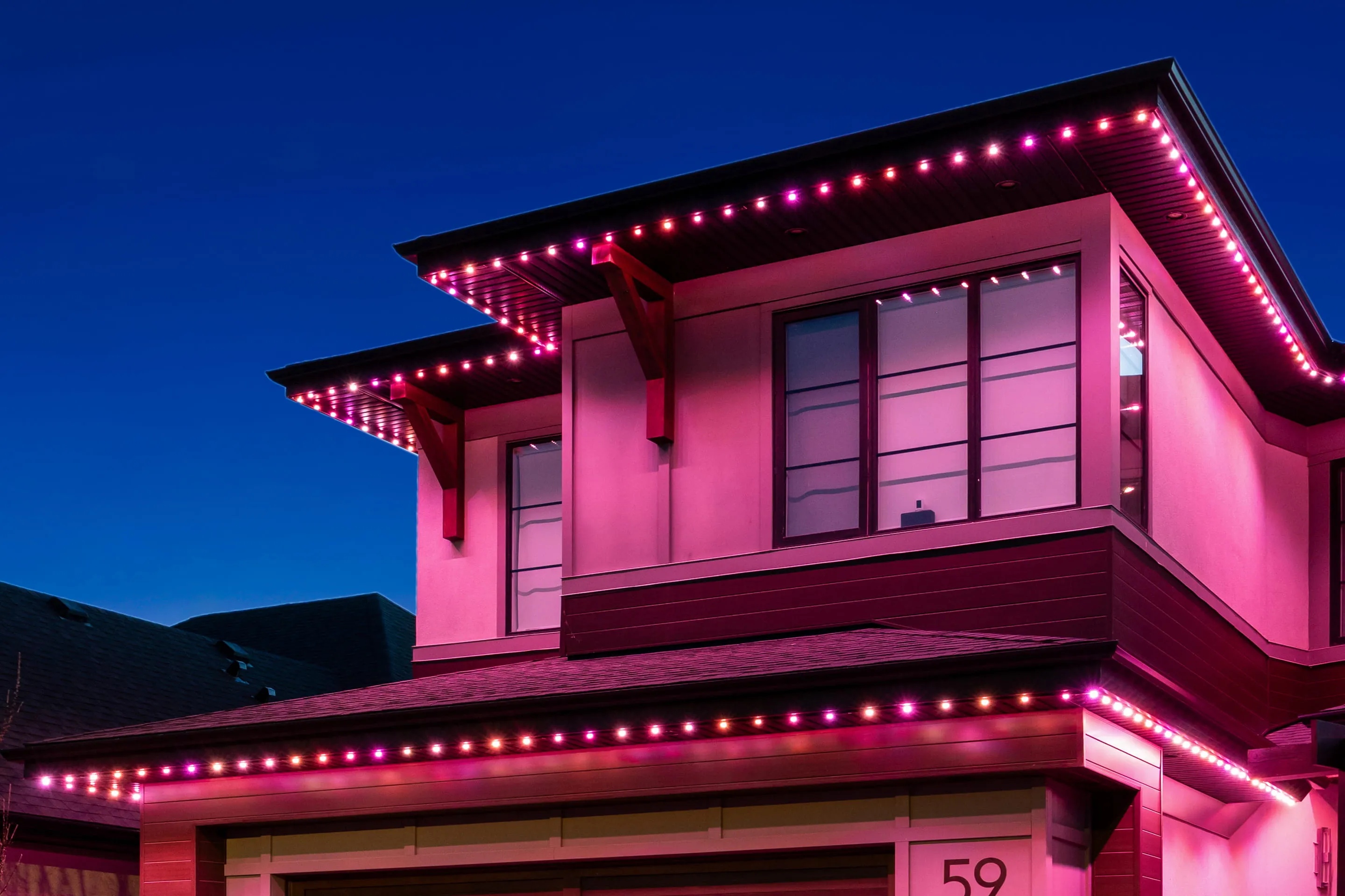 Modern house lit pink along every roofline